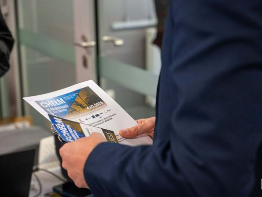 Osoba trzyma w rękach plan konferencji i identyfikator