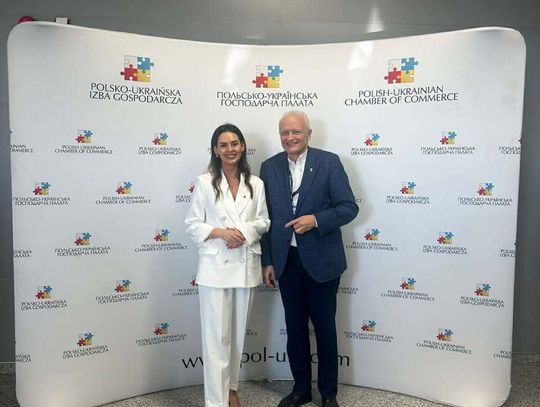 Dwie osoby stoją na tle ścianki z napisem Polsko-Ukraińska Izba Gospodarcza