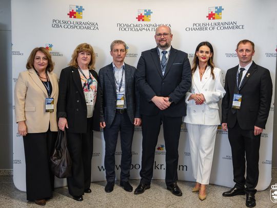 Grupa osób stoi na tle ścianki z napisem Polsko-Ukraińska Izba Gospodarcza